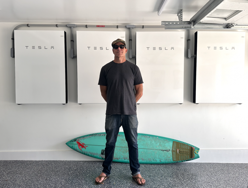 man stands in front of tesla power wall